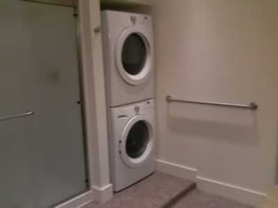 bathroom shower with stacking washer and dryer